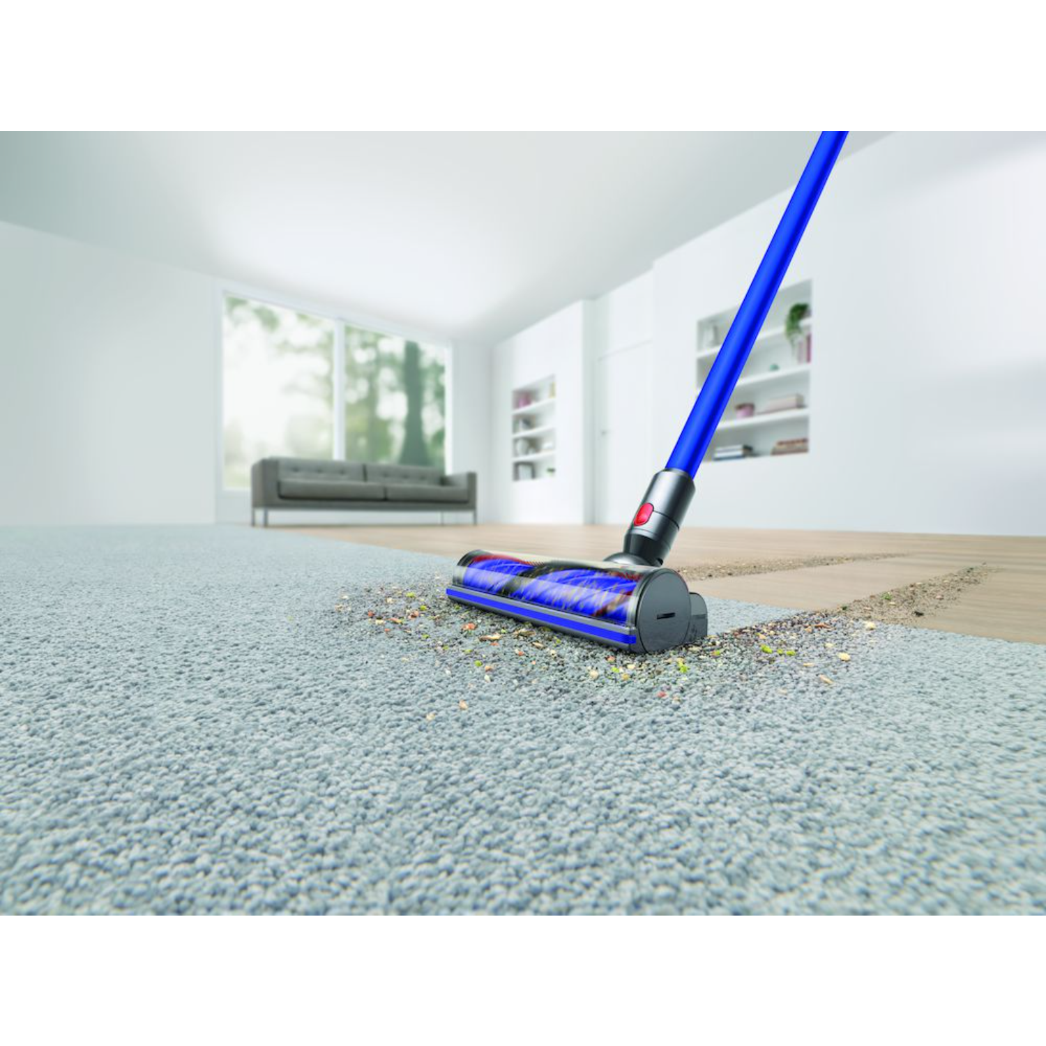 A vacuum cleaner is cleaning a carpet. Debris is visible on the carpet.