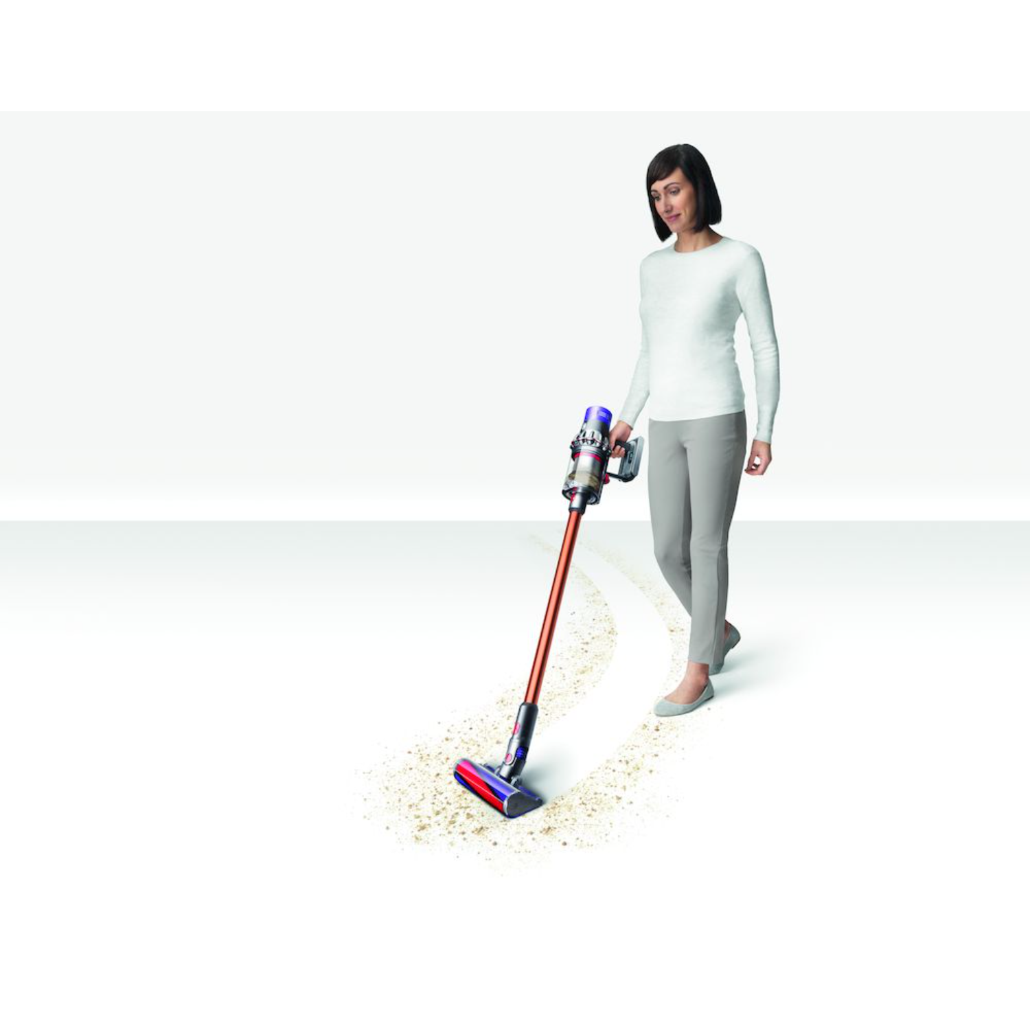 Vrouw die een witte vloer stofzuigt met een rode en blauwe Dyson stofzuiger.