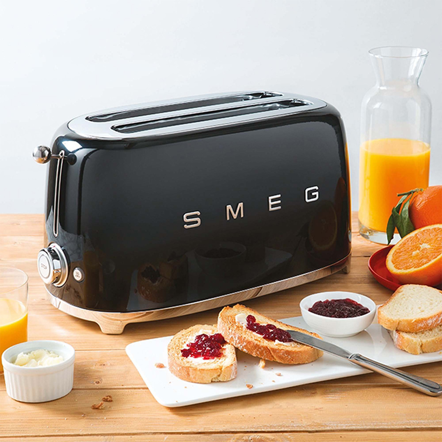 Tostapane SMEG nero con due fette di toast con marmellata e succo d'arancia.