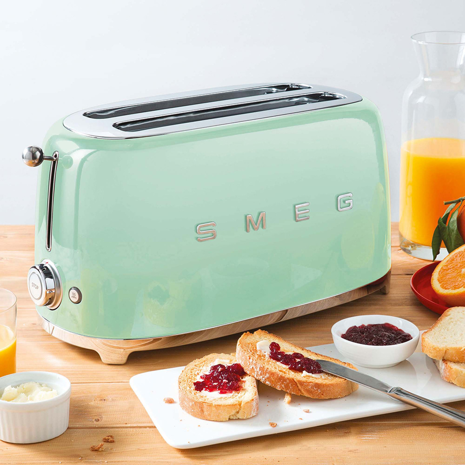Un tostapane Smeg verde menta con due fette di pane tostato con marmellata e burro.