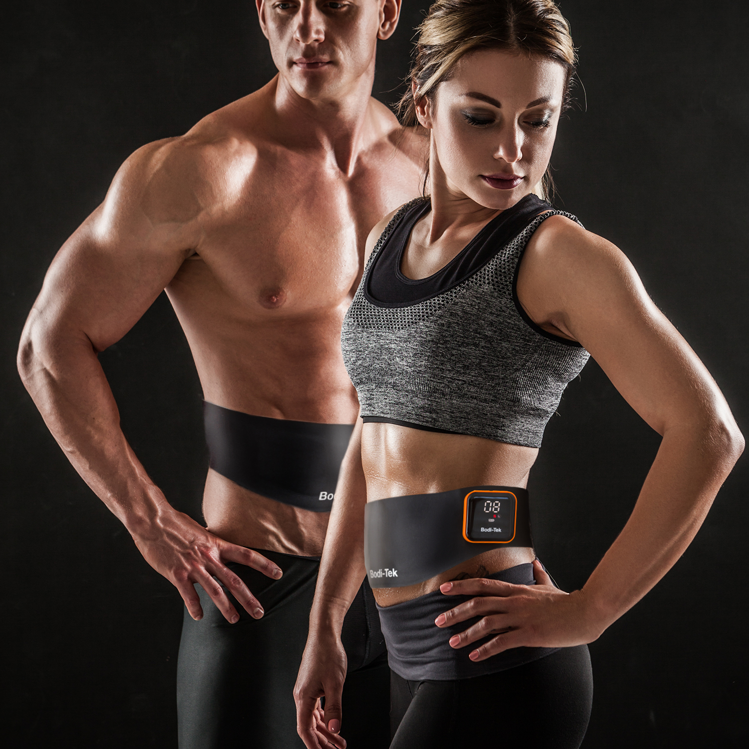 Two people wearing black body wraps, a woman has a device on her abdomen.