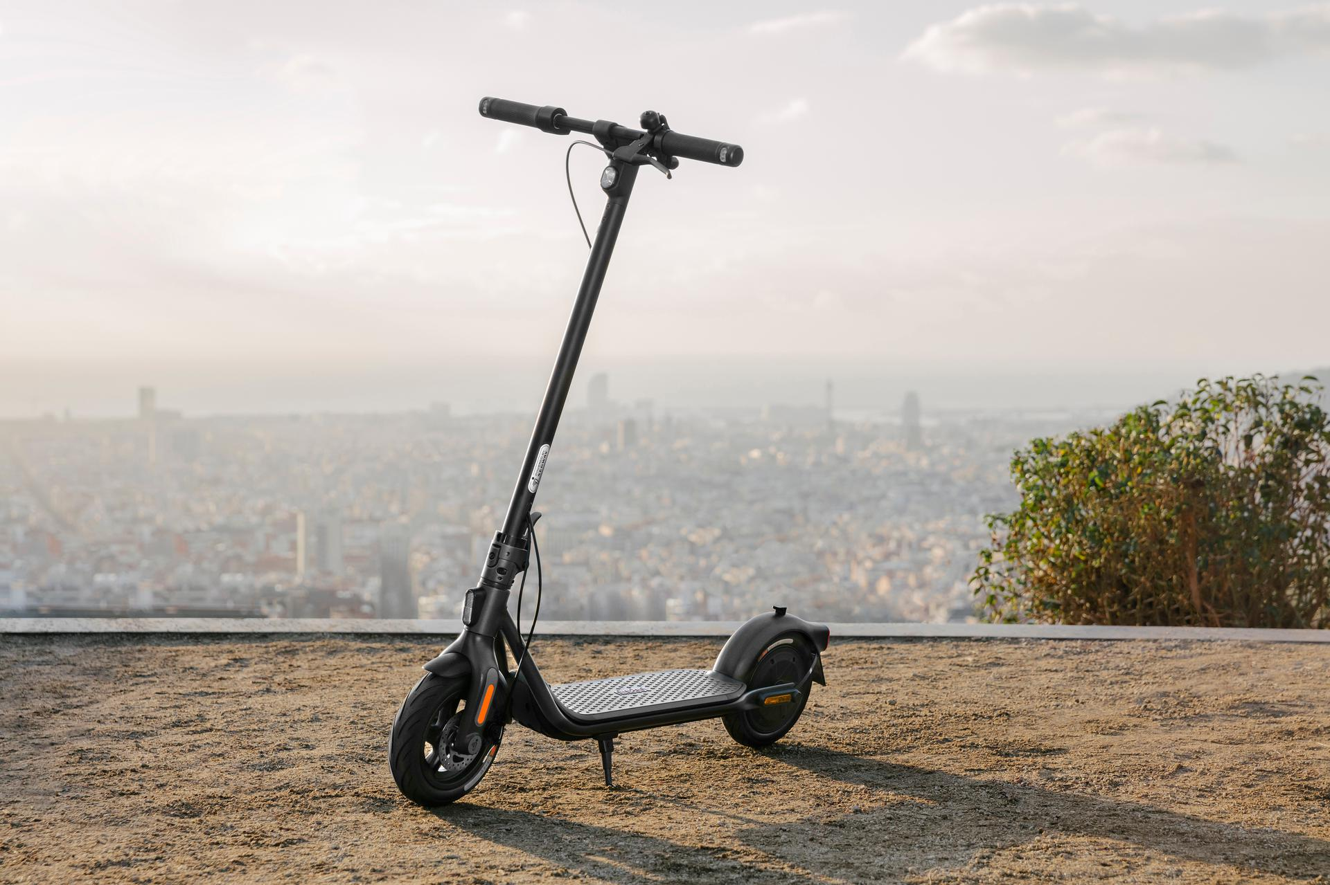 Schwarzer Elektroroller auf einem Hügel geparkt, mit Stadtlandschaft im Hintergrund.