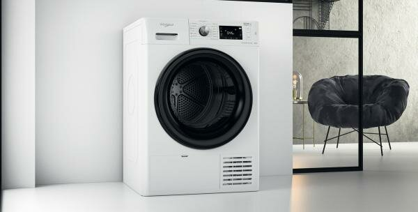 Biała suszarka Whirlpool w pokoju. Czarne krzesło i element dekoracyjny są w tle.