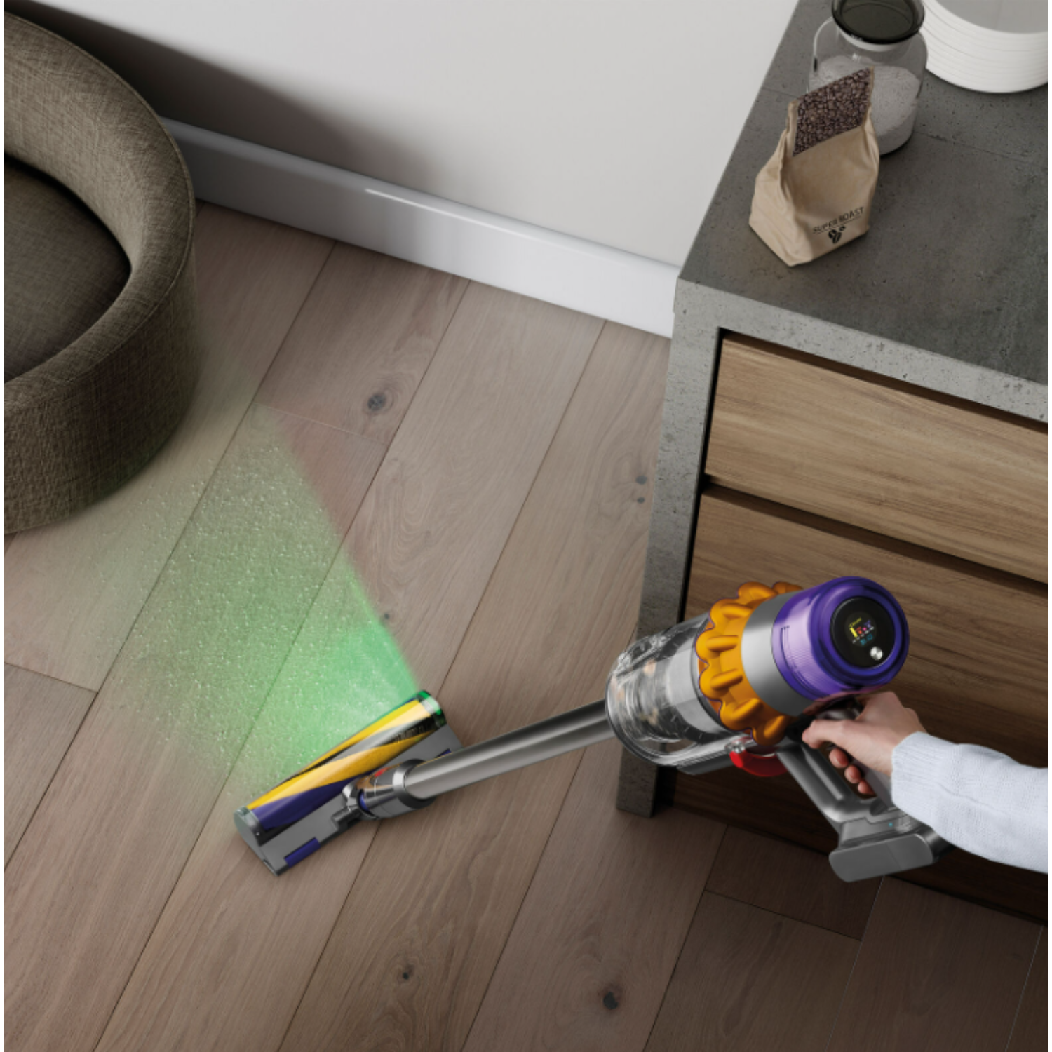 Personne aspirant avec un Dyson. Lumière verte émise par la brosse. Plancher en bois.