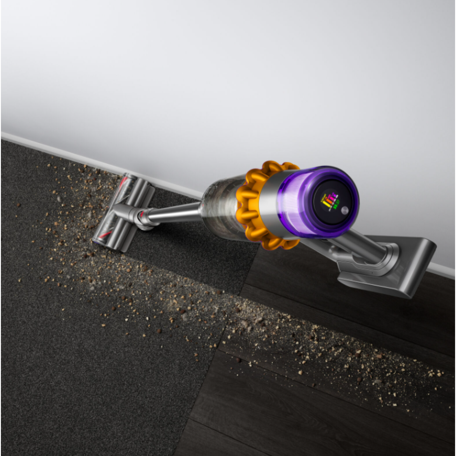 Un aspirateur sans fil nettoyant un sol avec des débris. Détails jaunes et violets.