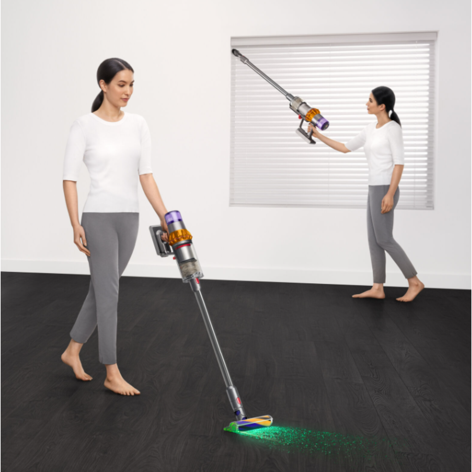 Femme passe l'aspirateur avec un aspirateur sans fil, autre femme en arrière-plan.