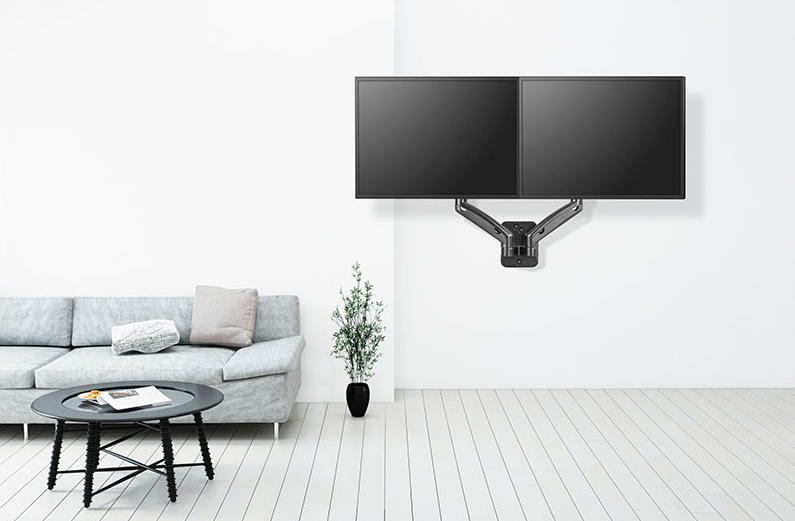Két fekete TV a falra szerelve, kanapéval és asztallal. Fehér falak és fa padló egy világos szobában.