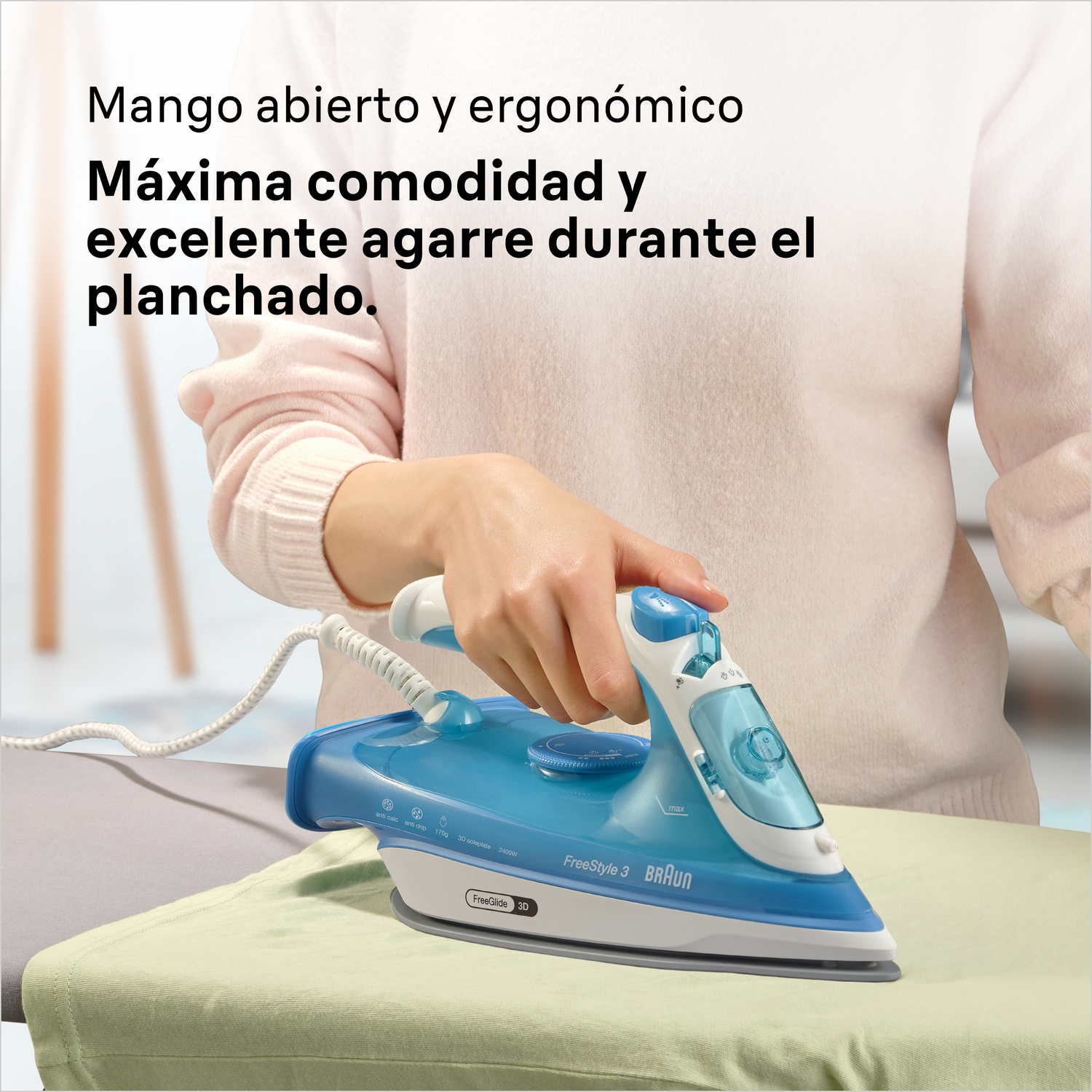 Una mano usa una plancha azul y blanca sobre tela verde en una tabla de planchar.