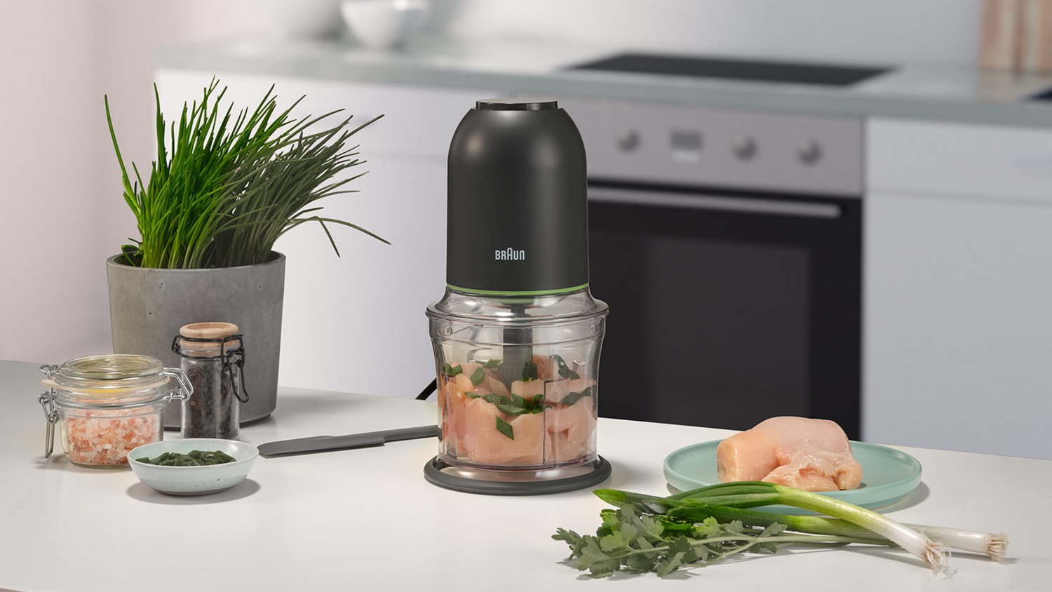Procesador de alimentos Braun negro, con pollo picado y perejil.