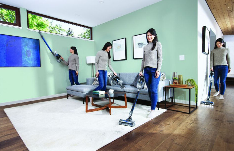 Kobieta odkurza salon. Inne kobiety odkurzają różne części pokoju.