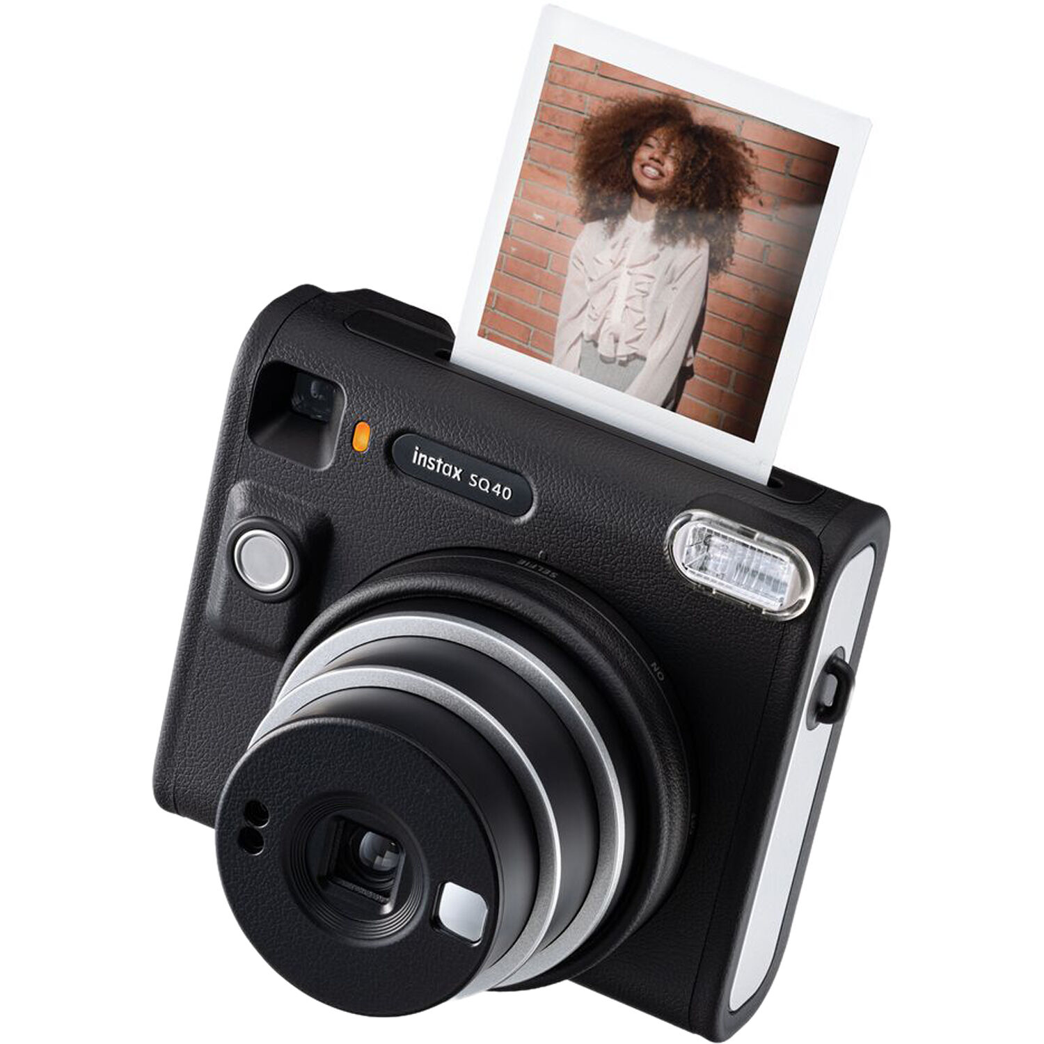 Black instant camera with a picture coming out. A woman is in the photo, with a brick wall background.