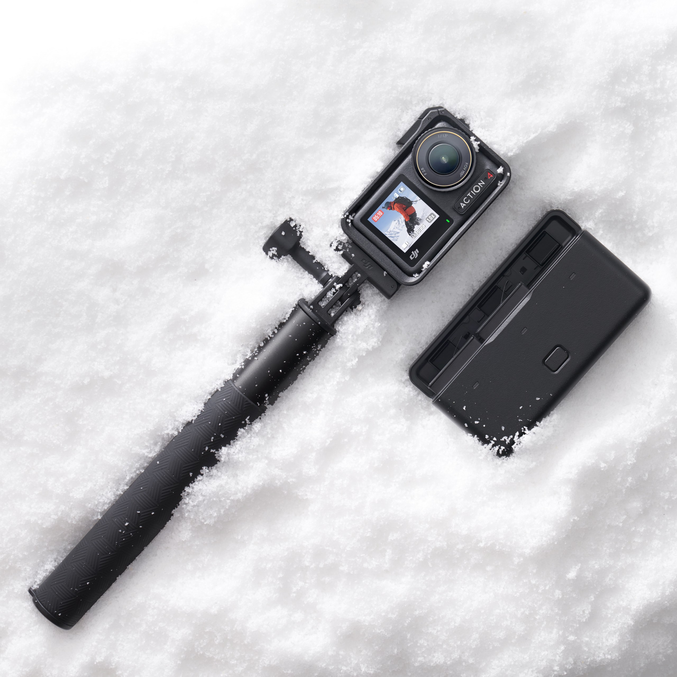 Action-Kamera auf einem Selfie-Stick im Schnee, mit einer Hülle.