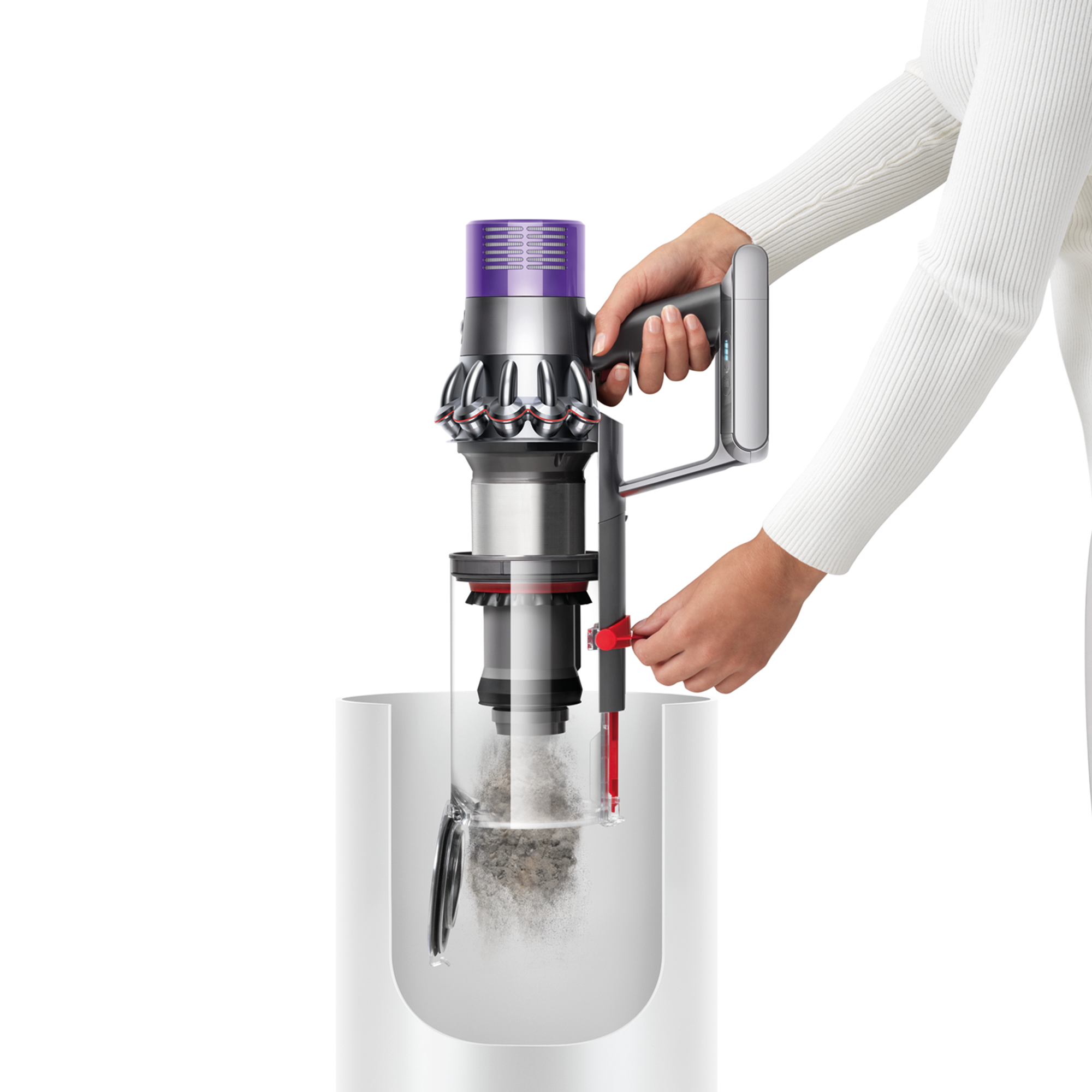 Eine Person entleert einen Dyson-Staubsauger in einen weißen Behälter.