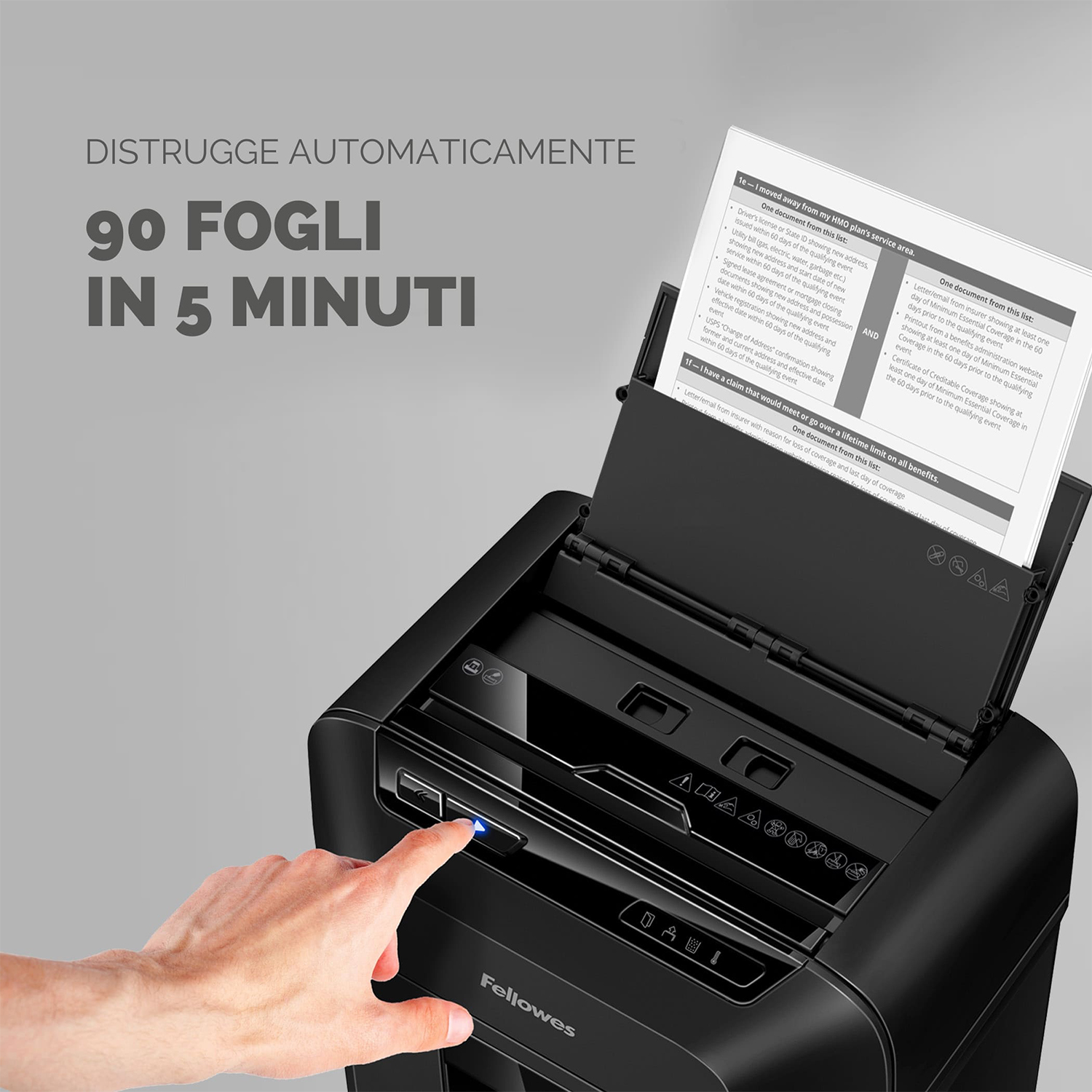 Un distruggidocumenti Fellowes nero. Una mano preme il pulsante di accensione e la carta viene distrutta.