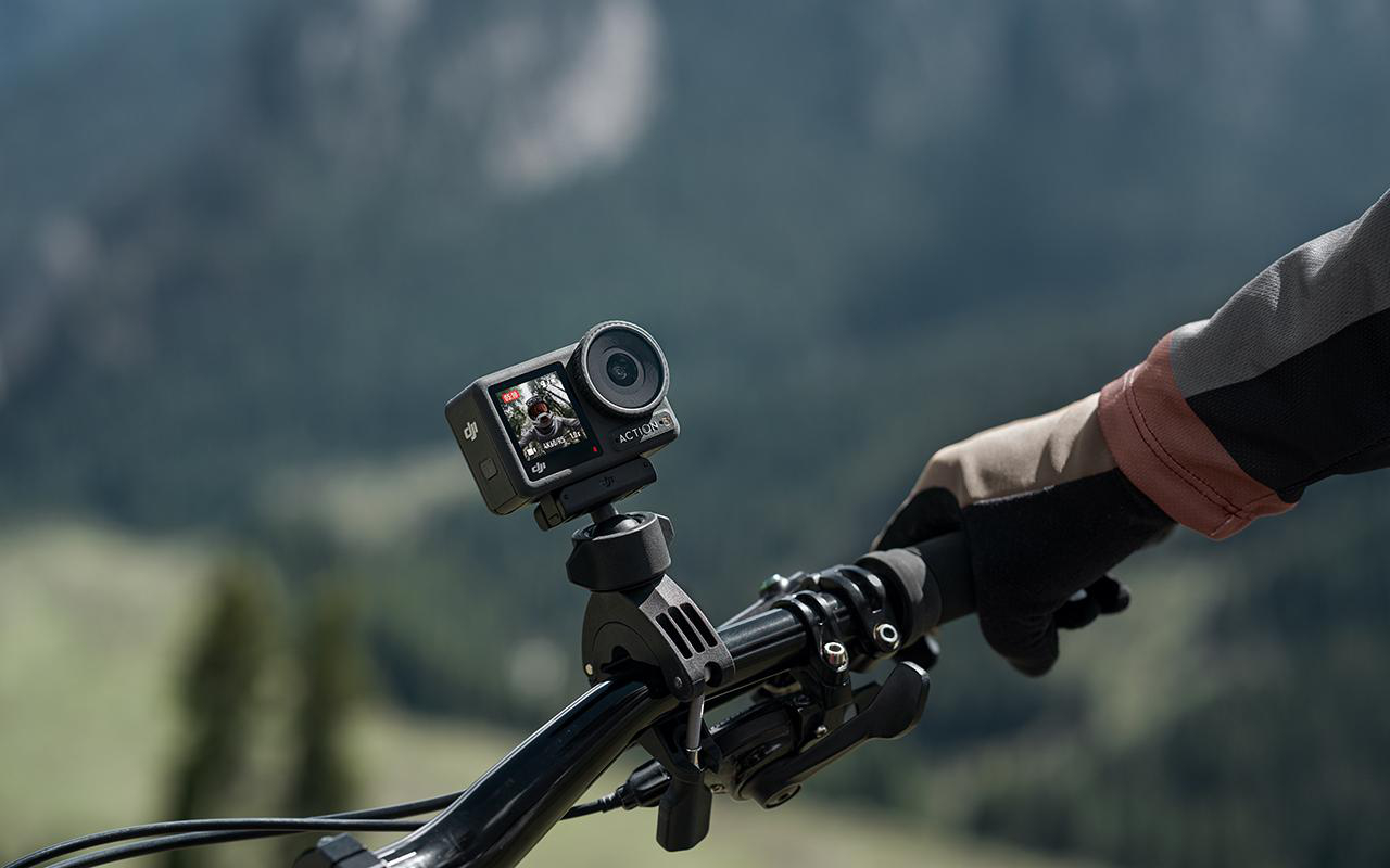 Action-Kamera an Fahrradlenker montiert, die eine Berglandschaft aufzeichnet.