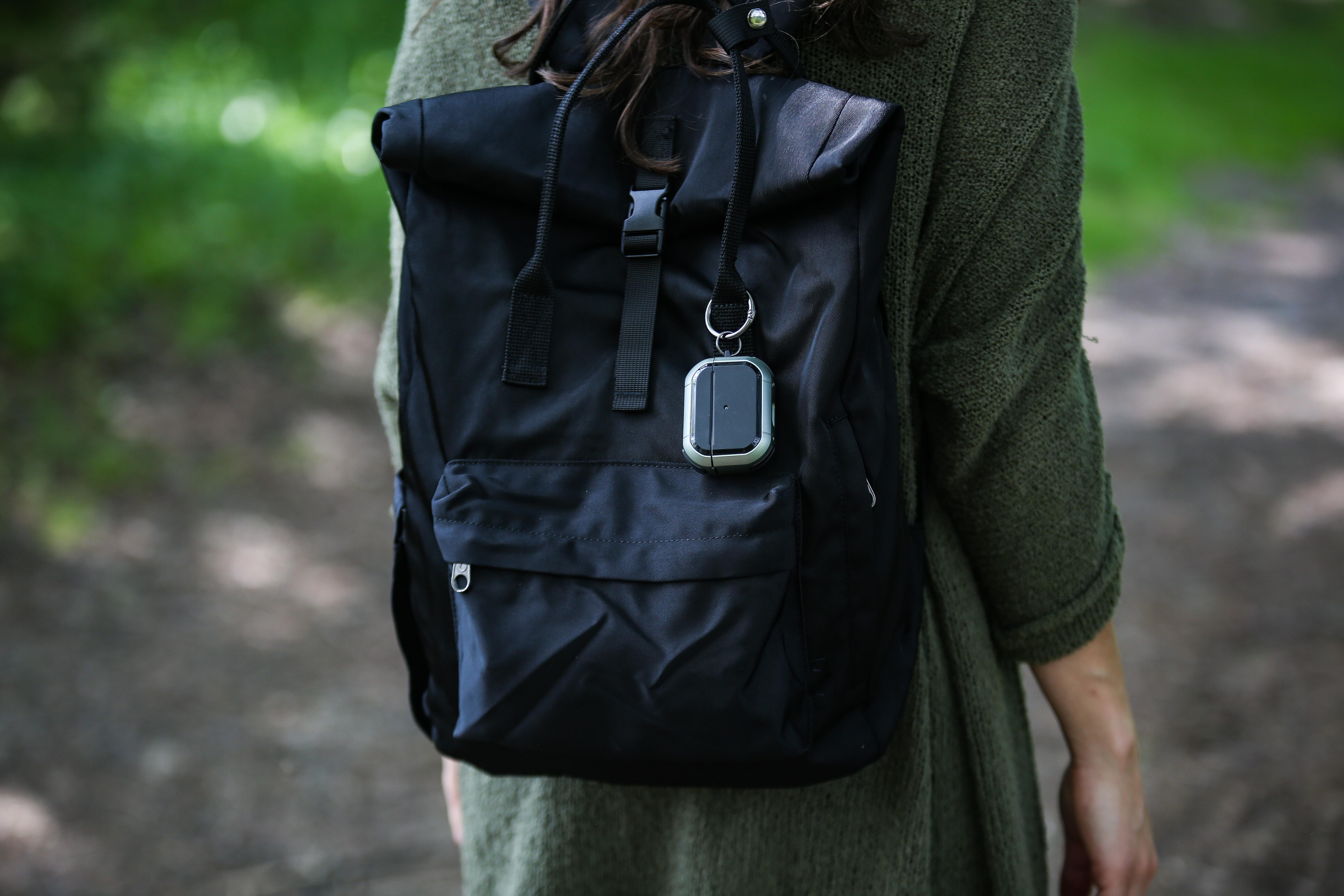 Eine Frau mit grünem Pullover, schwarzem Rucksack und Schlüsselanhänger.