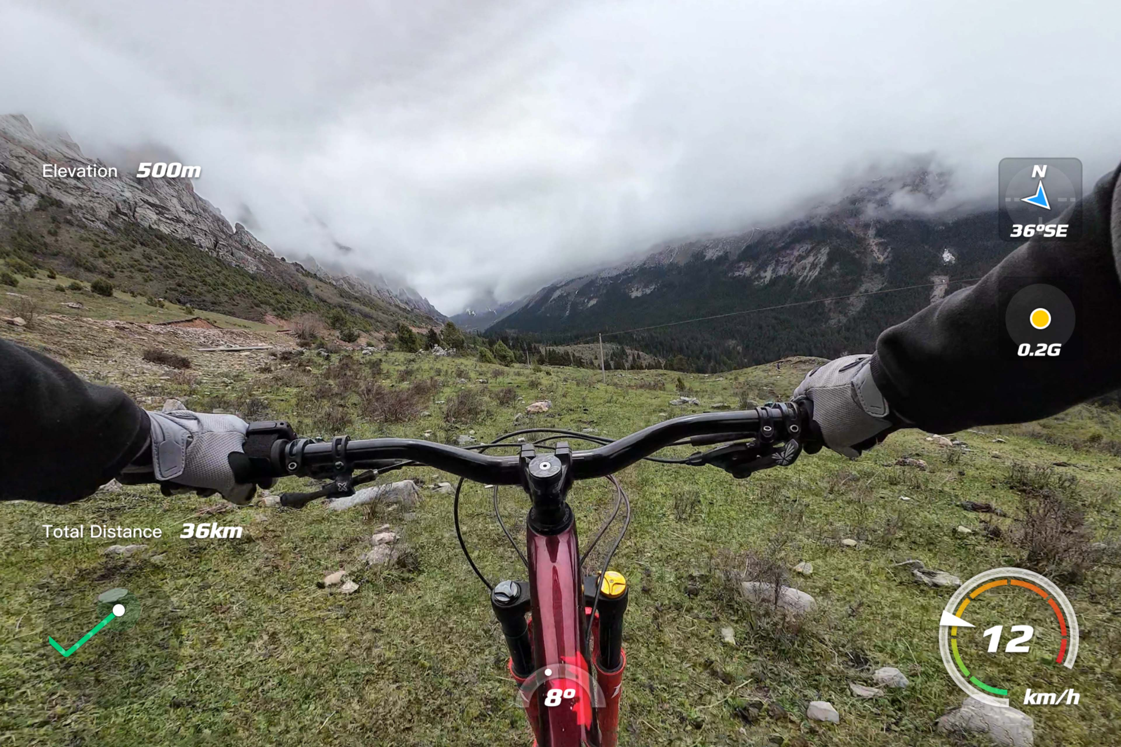 Blick des Mountainbikers: Lenker, bewölkter Himmel, grünes Gelände und Informationsanzeige oben rechts.