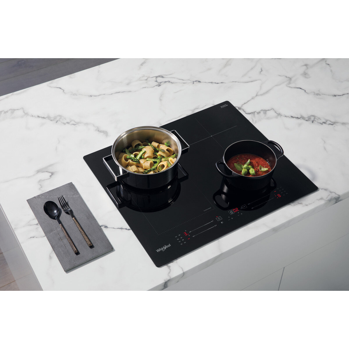 Czarna płyta indukcyjna z dwoma garnkami, jeden z makaronem.