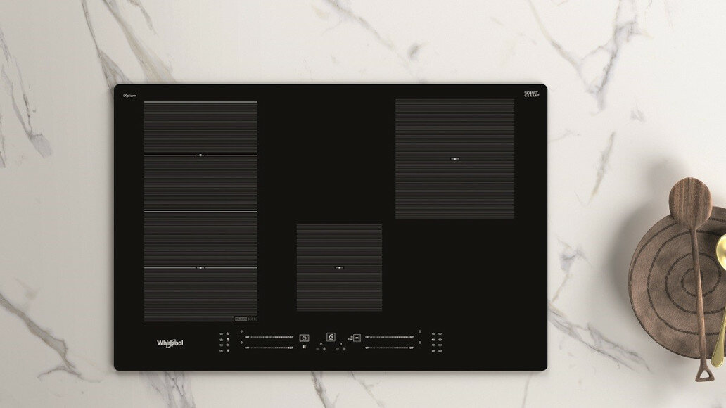 Czarna płyta indukcyjna z czterema strefami gotowania, biały blat z drewnianymi łyżkami.