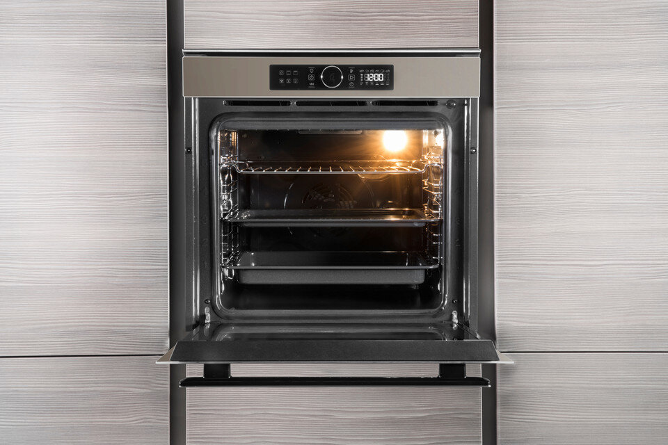 Otwarty piekarnik pokazuje wewnętrzne ruszty i światło. Z zewnątrz wykończenie imituje drewno.