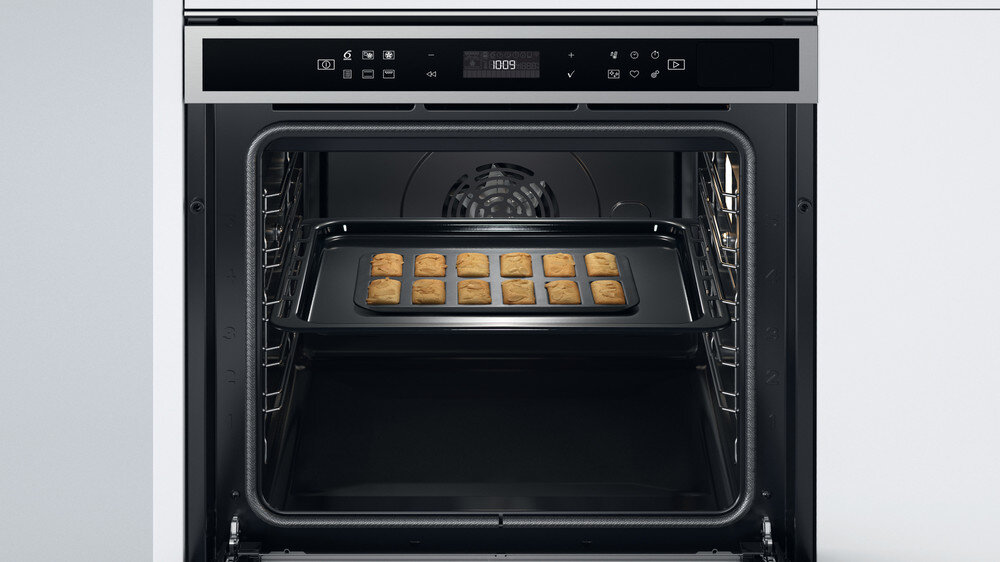 Wnętrze piekarnika z blachą z ciasteczkami. Panel sterowania u góry.