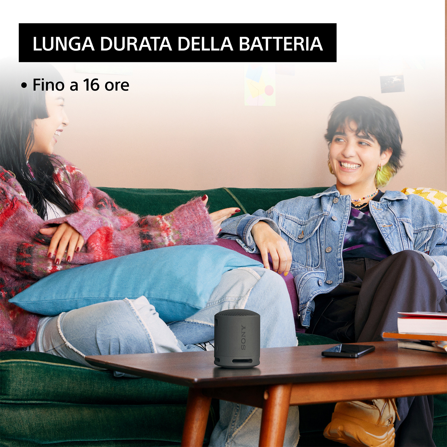 Due persone su un divano verde, uno tiene un altoparlante nero. Testo: 'Lunga durata'.