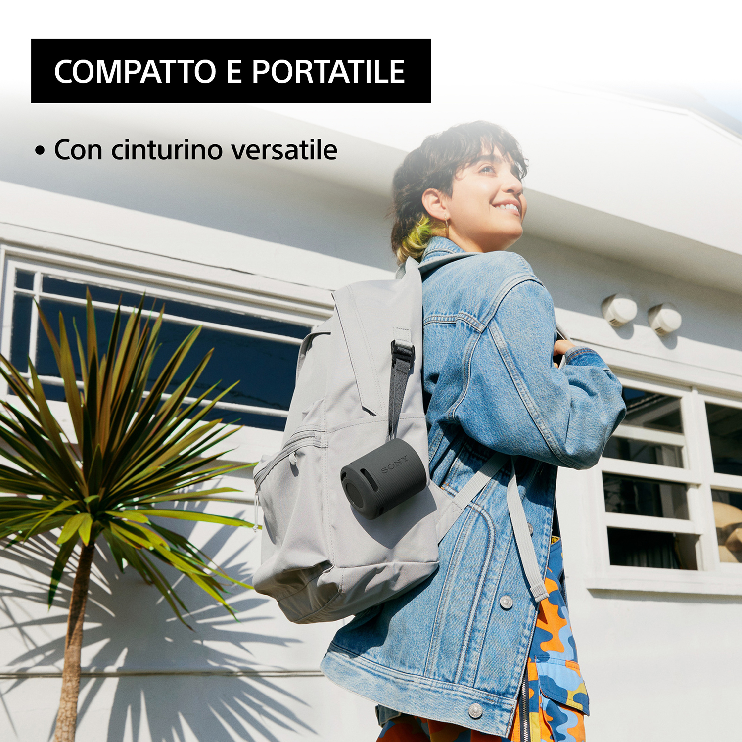 Giovane donna con uno zaino che tiene un altoparlante portatile.