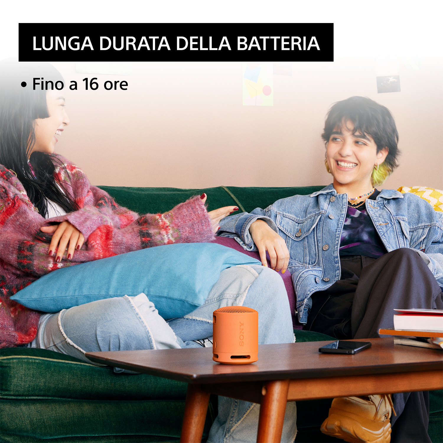 Due persone su un divano con un altoparlante arancione su un tavolo.
