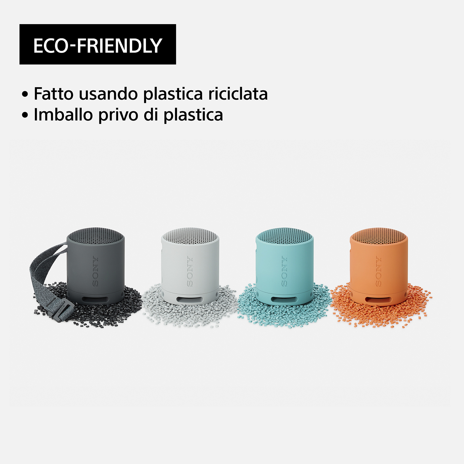 Quattro piccoli altoparlanti colorati su un letto di piccoli ciottoli scuri. Marchio eco-friendly in alto.