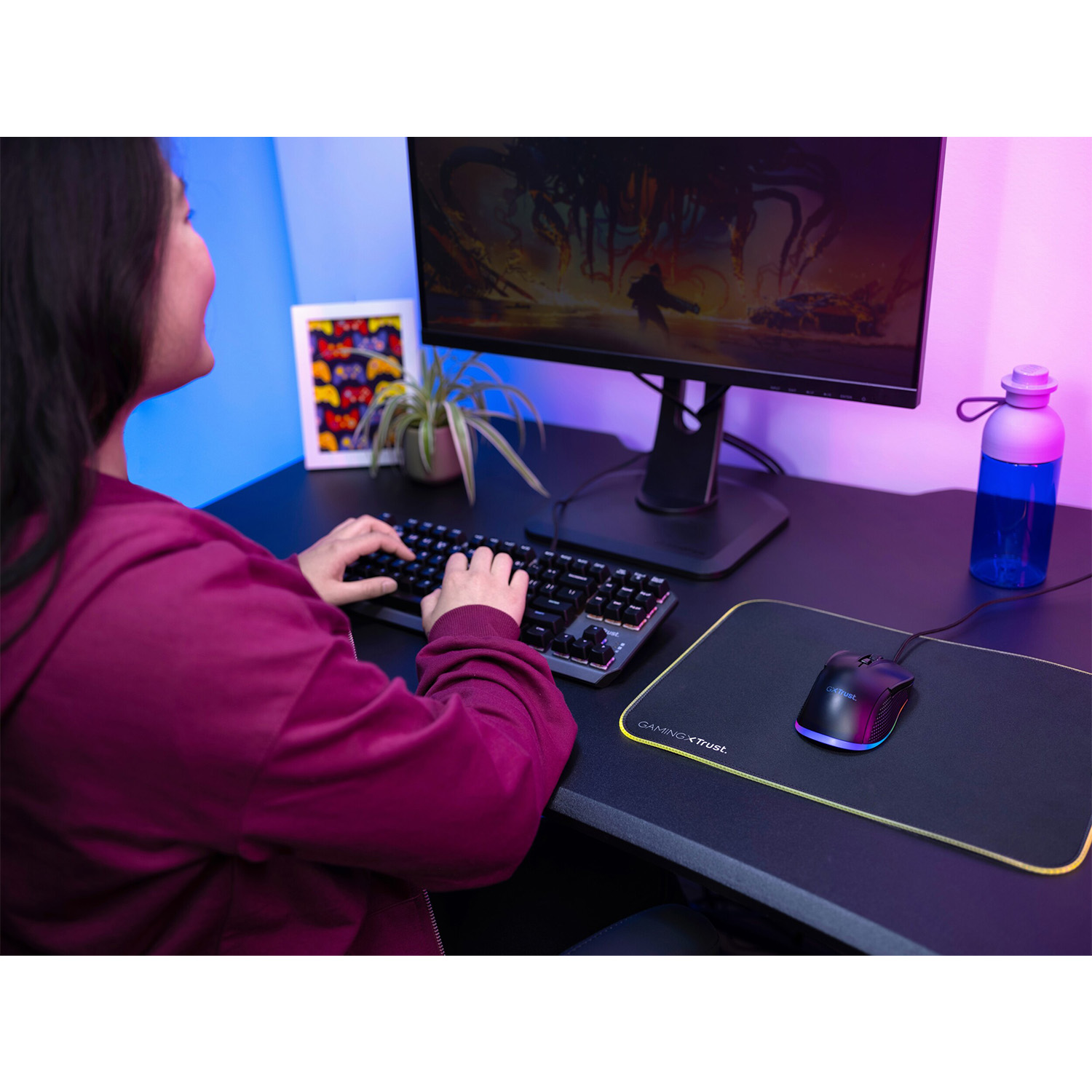 Una donna gioca al computer, usando tastiera e mouse. La stanza è illuminata da luci colorate.