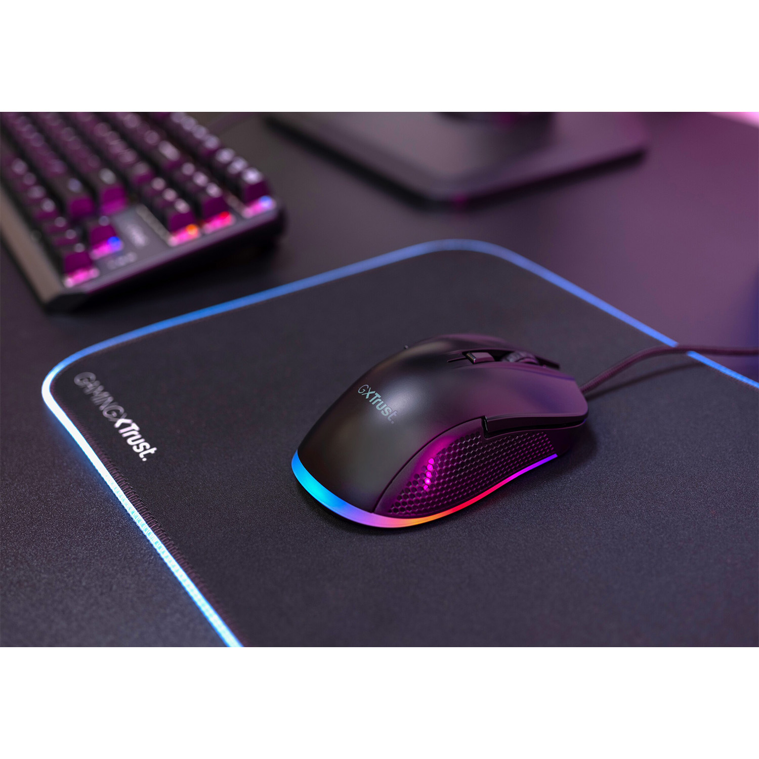 Mouse da gaming su un tappetino con tastiera sullo sfondo. Il mouse ha illuminazione RGB.