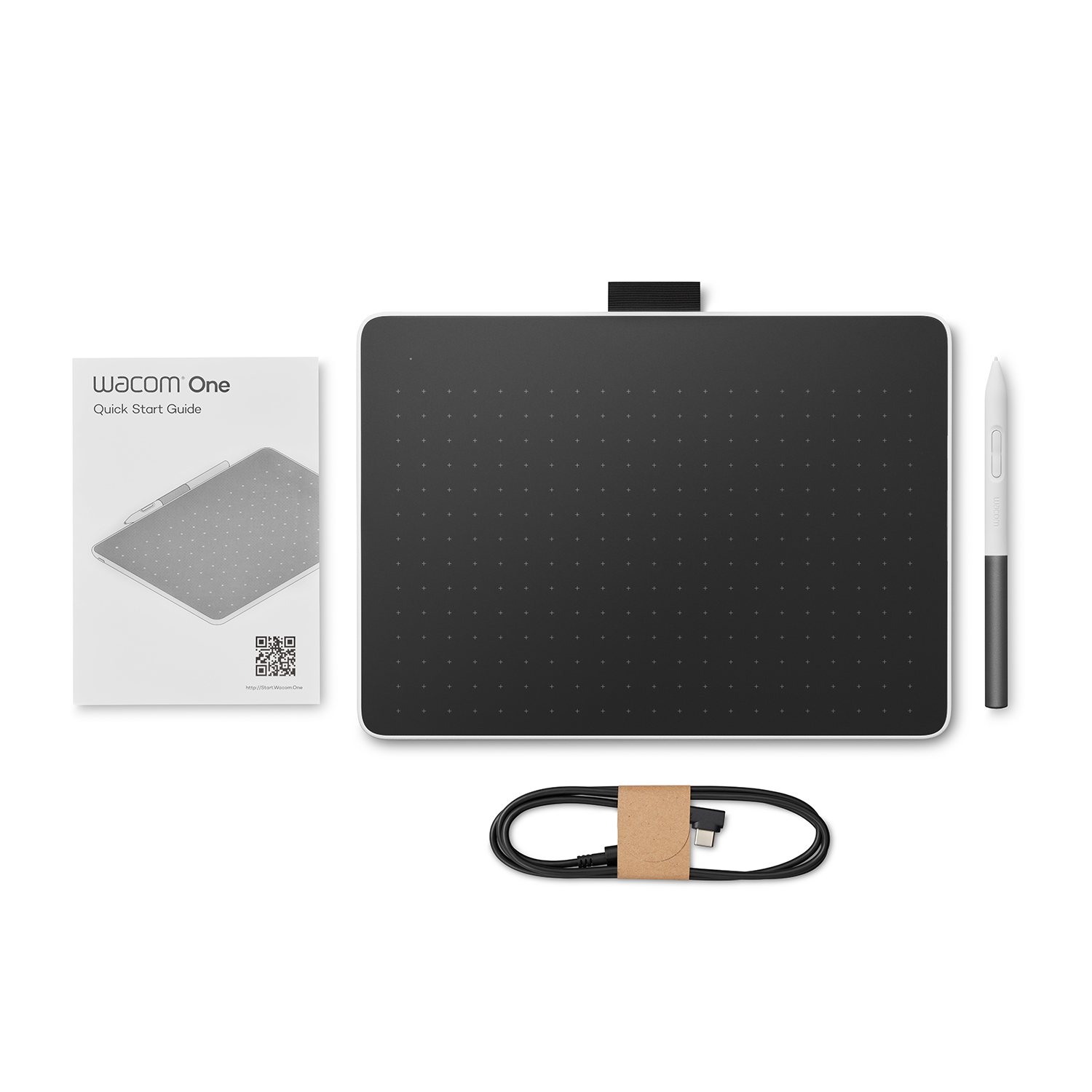 Un tablet Wacom One con penna, guida rapida e cavo USB su una superficie bianca.