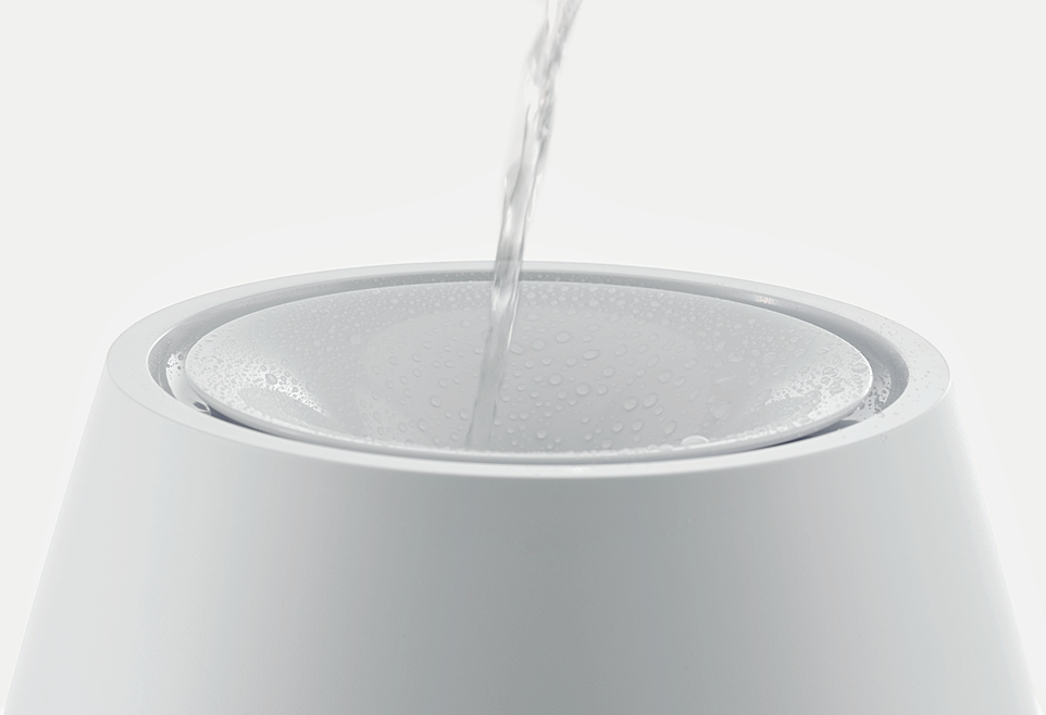 Wasser gießt in einen weißen Napf. Ein klarer Wasserstrahl füllt die Schüssel.