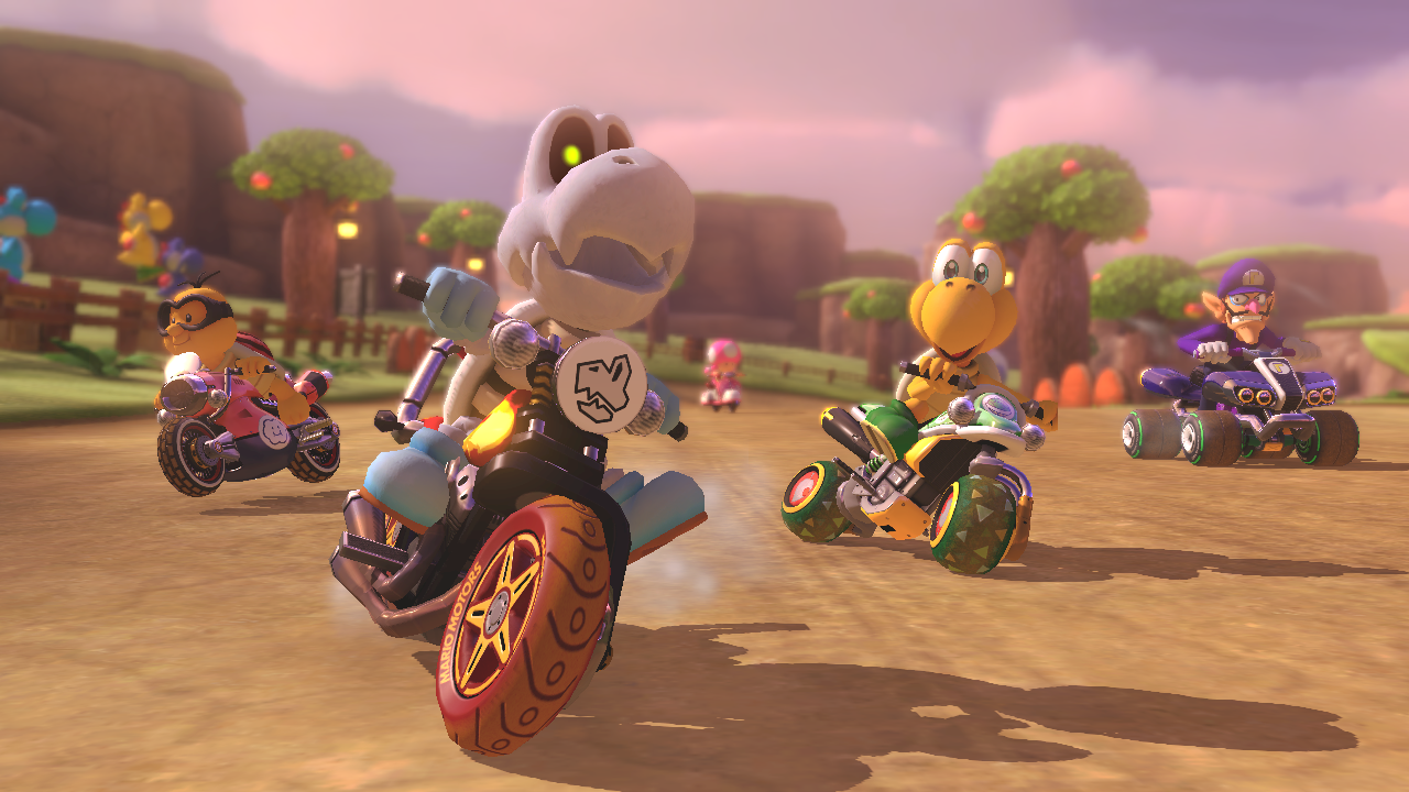 Mario Kart characters racing on a dirt track, sunny day.