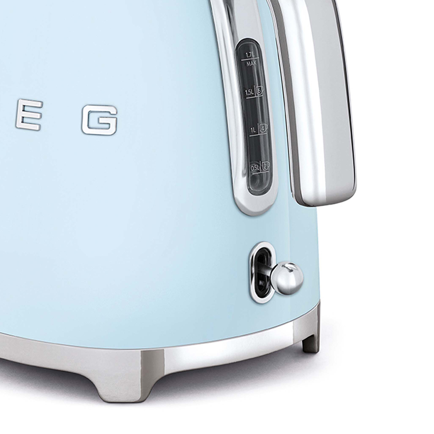 Primo piano di un bollitore Smeg blu, che mostra il livello dell'acqua e una maniglia cromata. Sfondo bianco.