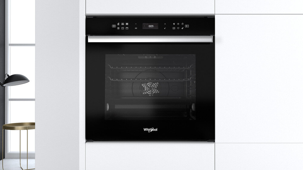 Czarny piekarnik do zabudowy w białej kuchni. Logo Whirlpool jest widoczne na piekarniku.