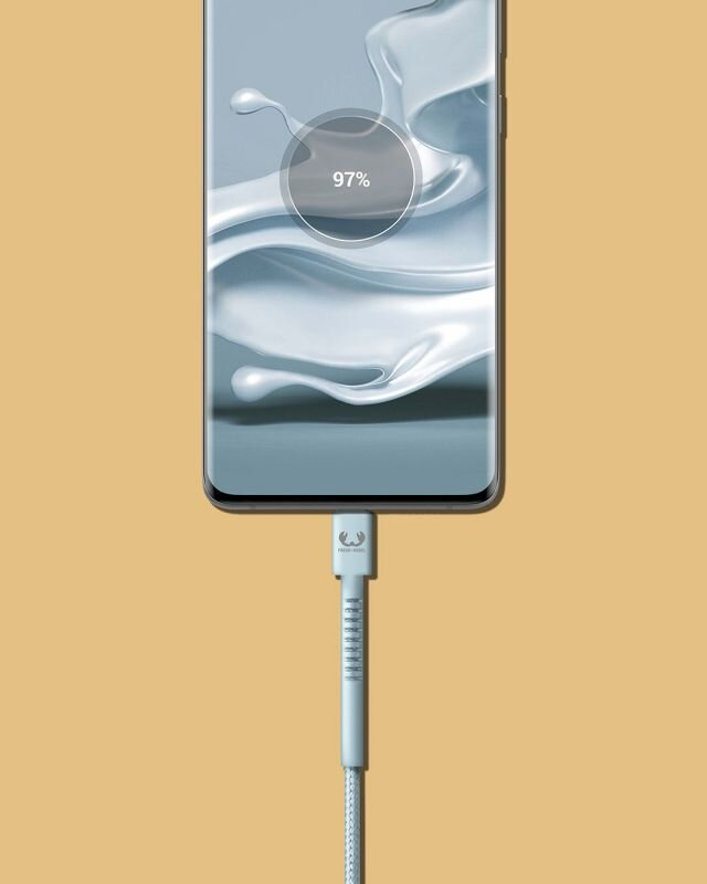 Telefon ładujący się kablem. Pokazuje 97% baterii. Tło jest w kolorze beżowym.