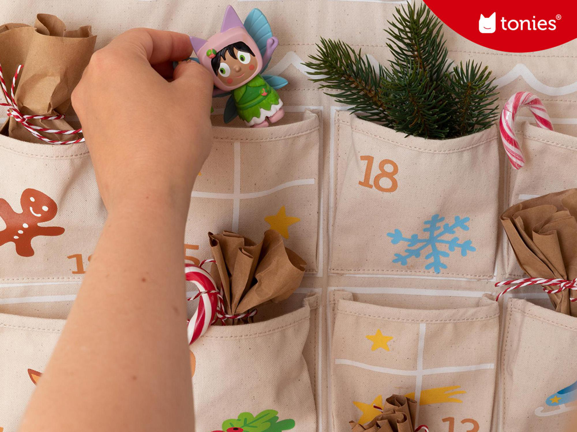 Eine Hand, die eine Tonie-Figur in eine Adventskalendertasche mit der Nummer 18 legt.