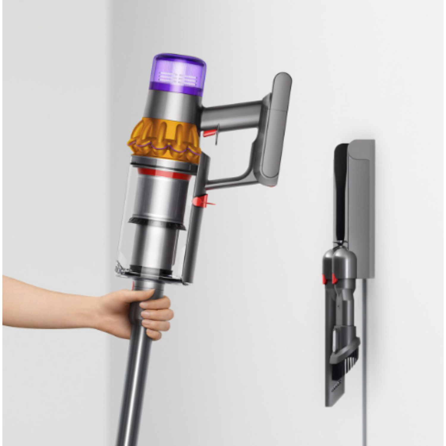 Hand holding a Dyson vacuum and charger.