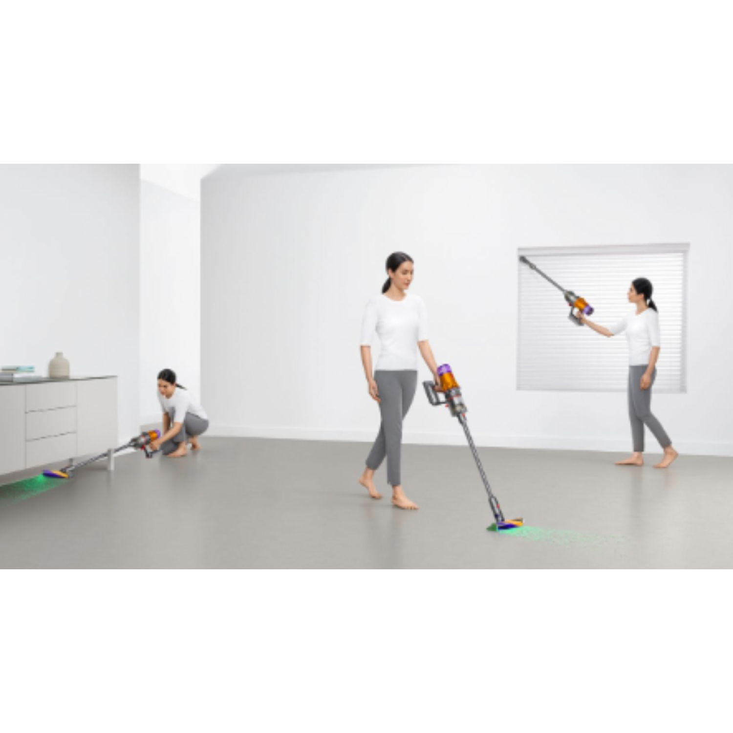 Three women vacuuming a room. One is standing, two are using the vacuum cleaner.