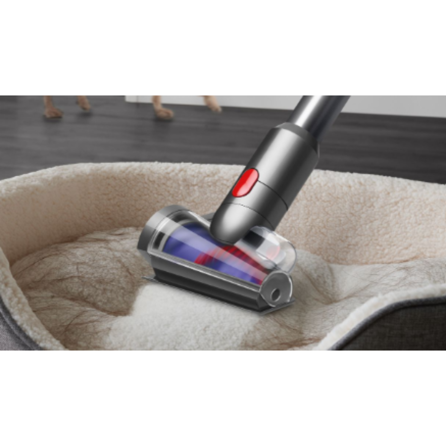 Vacuum head cleaning a dog bed. Shows rotating brush and hair being sucked up.