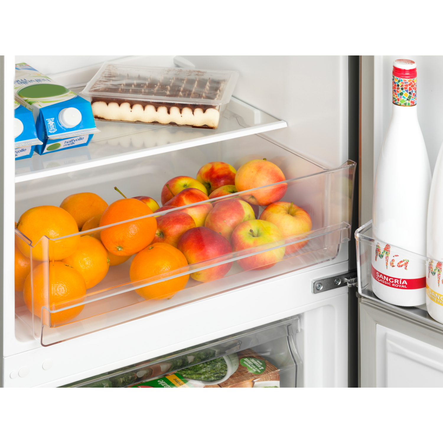 Refrigerator interior with fruits and beverages. Oranges, apples, and juice cartons are visible.