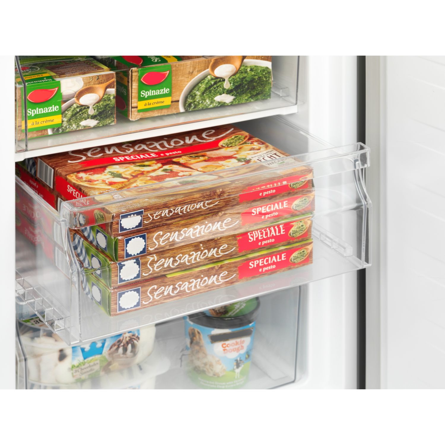 Refrigerator interior with food on shelves. Frozen pizzas and spinach. White interior. Transparent shelves.