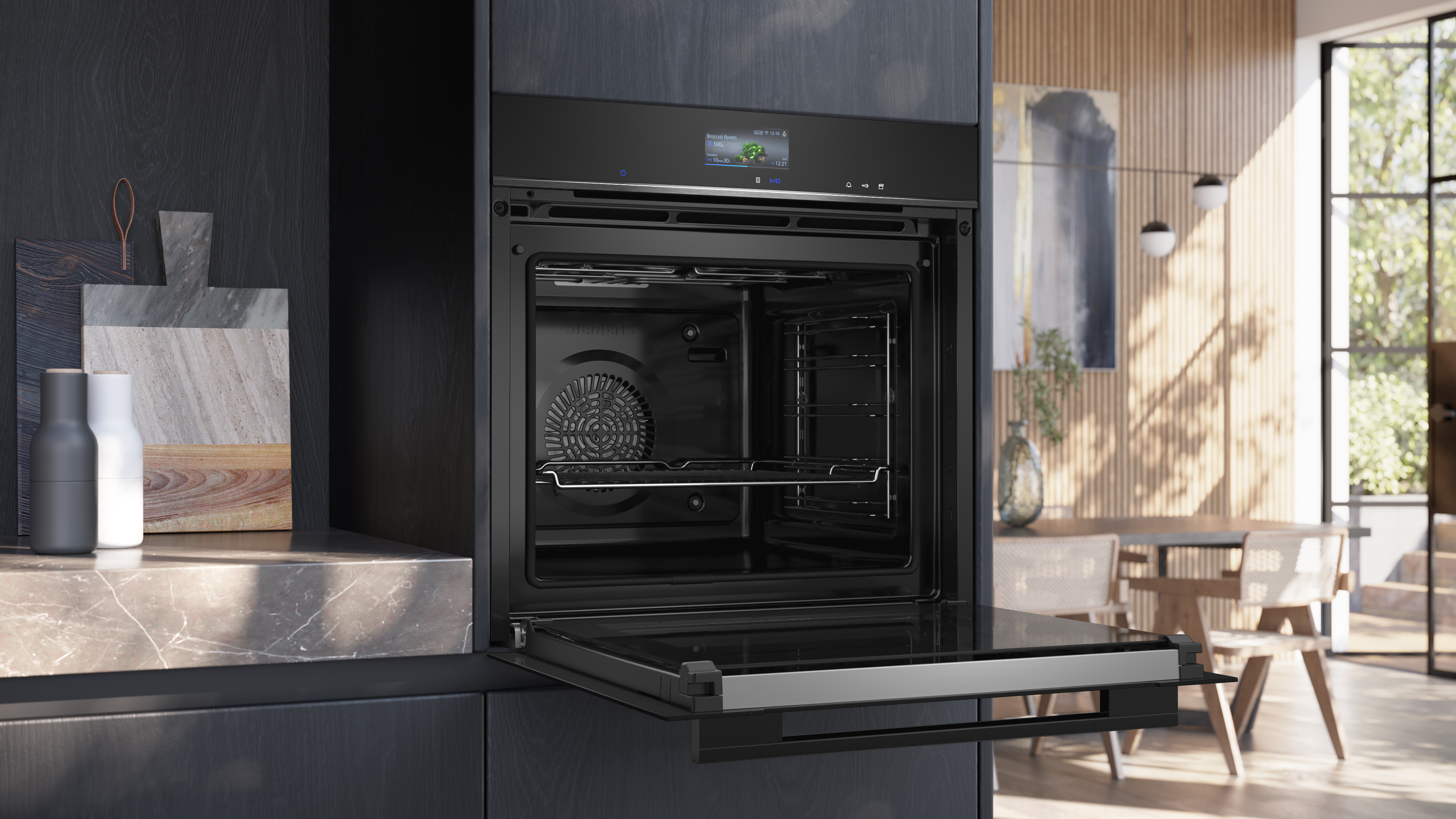 Offener Backofen mit offener Tür, schwarzes Design, auf Marmor. Hinten: Esszimmer.