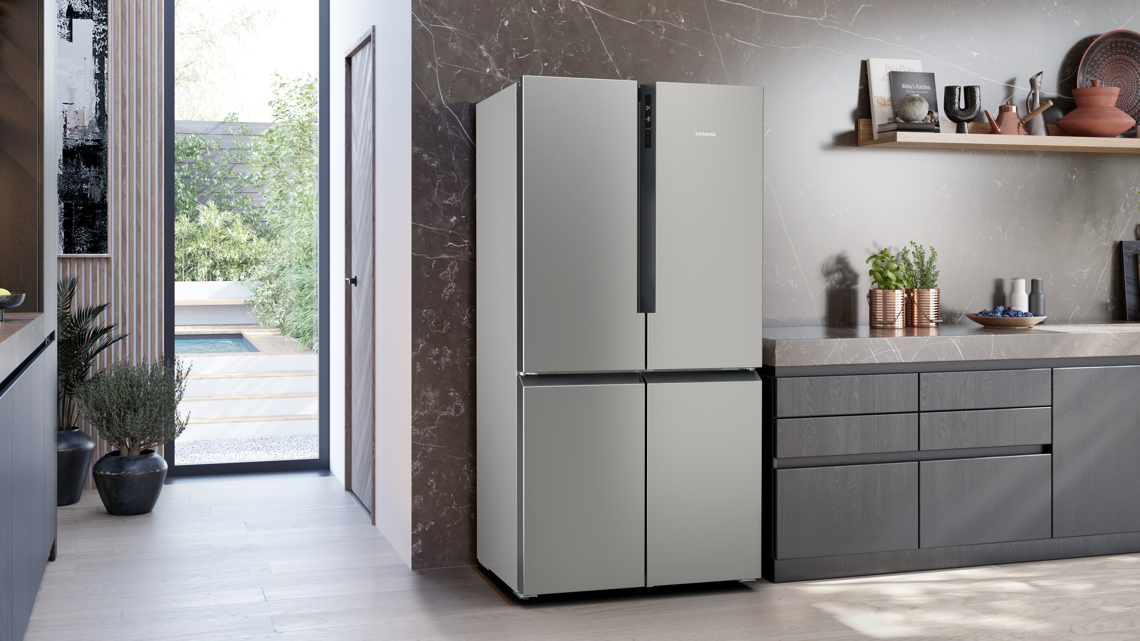Eine moderne Küche mit silbernem Kühlschrank. Der Kühlschrank hat vier Türen und steht neben einem Fenster.