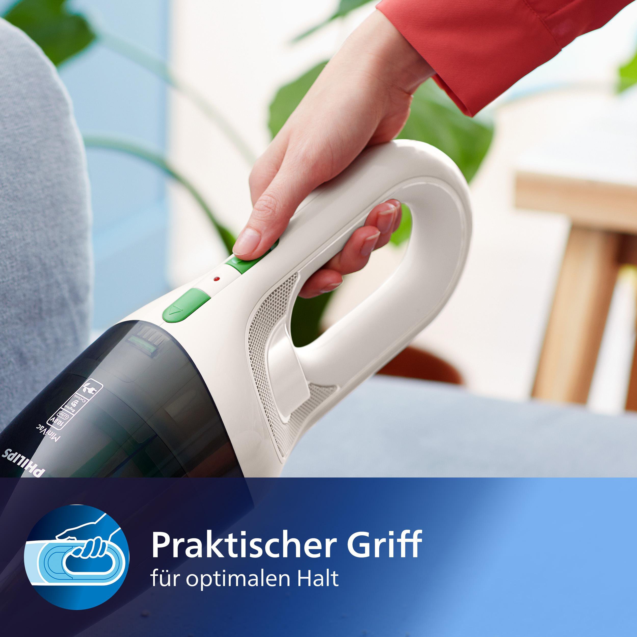 Hand hält weißen und schwarzen Staubsauger. Roter Ärmel, grüne Taste, blauer Hintergrund und Textbanner.