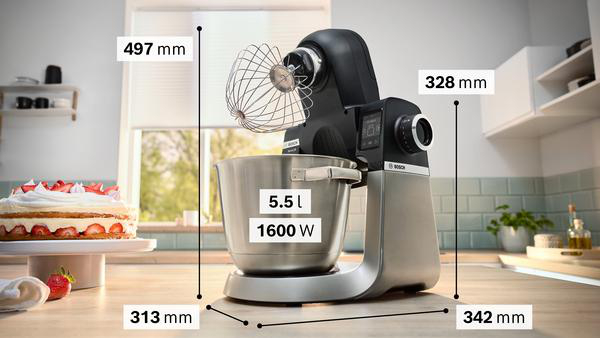 Küchenmaschine mit Abmessungen. Schüssel, Schneebesenaufsatz, Kuchen im Hintergrund.