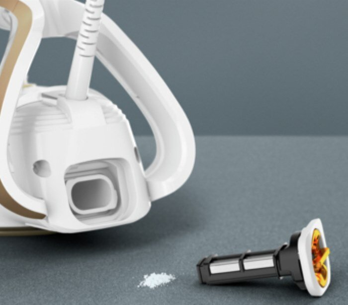 Zbliżenie białego i złotego żelazka z filtrem i proszkiem na szarej powierzchni.