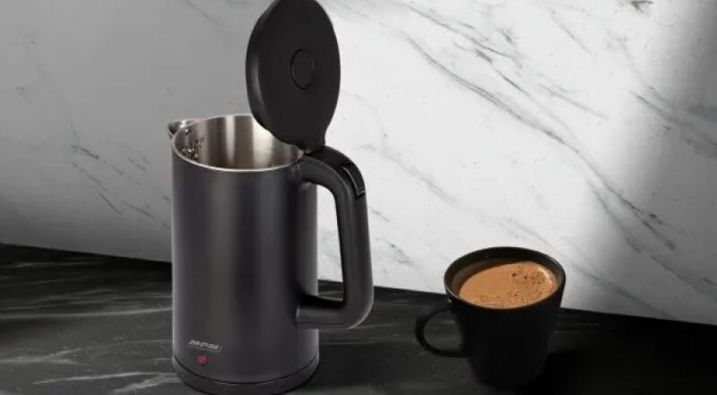 Czarny czajnik elektryczny z otwartą pokrywą i filiżanka kawy na marmurowej powierzchni.