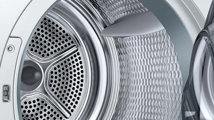 Zbliżenie wnętrza bębna pralki. Perforowany metal, błyszczący srebrny kolor.